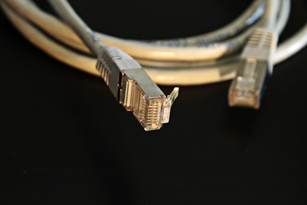 cablòaggio rame Detailed close-up of a network Ethernet cable showing connectors on a black background.